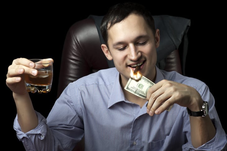 Man lighting his cigar with $100 note