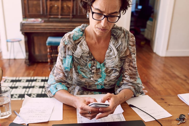 Older woman sitting at her desk comparing the best cell phone plans to save money