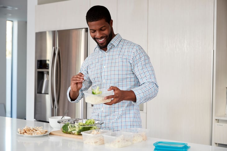 A man enjoying salad leftovers in the kitchen