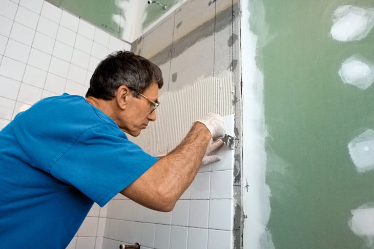 Man remodeling a bathtub with tile