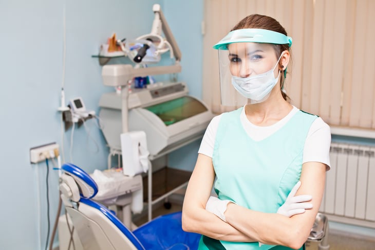 A dentist wearing protective gloves, face mask and face shield