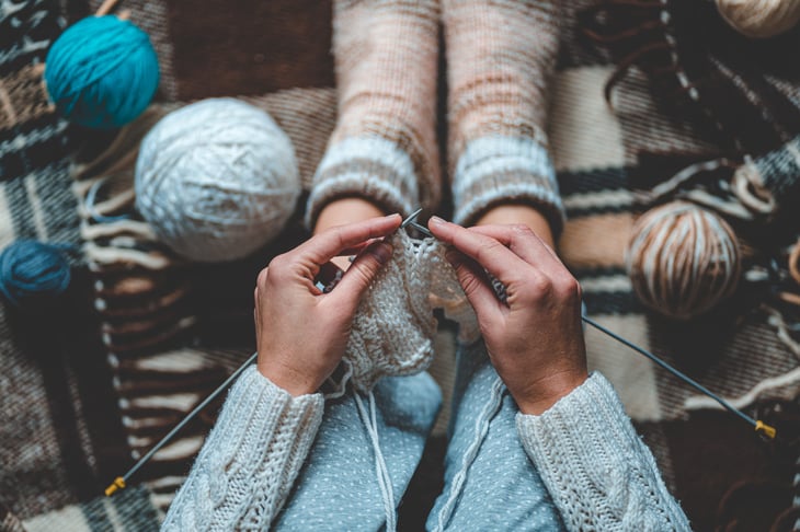 A woman knits yarn that was a comfort purchase during the coronavirus crisis
