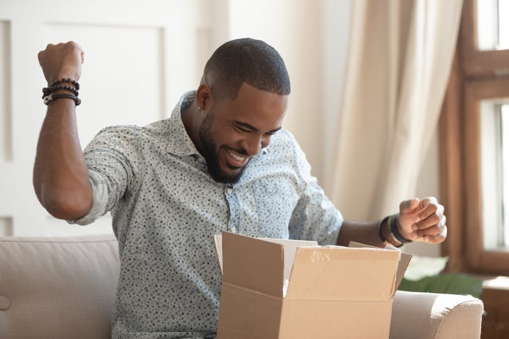 A man excitedly opening a comfort buy package during the coronavirus pandemic