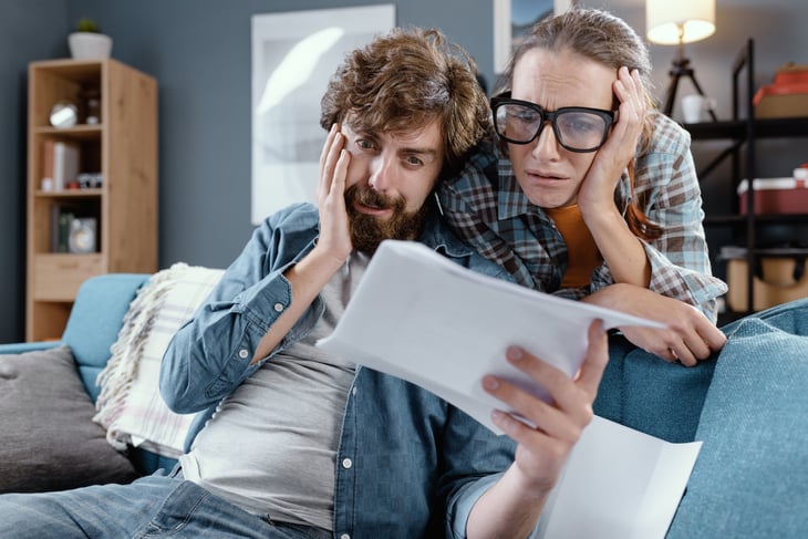 young couple sad shocked worried bills broke paycheck