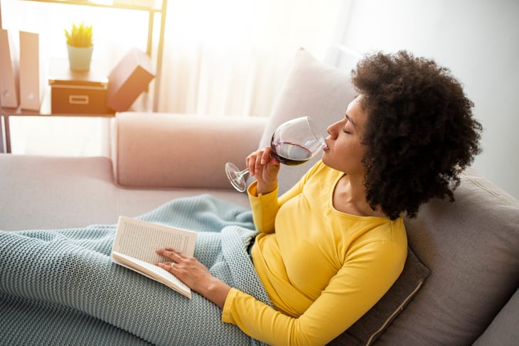 Woman drinking wine and reading a book