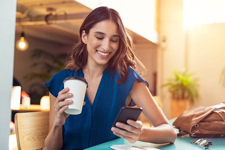 Woman happy with her phone and a coffee