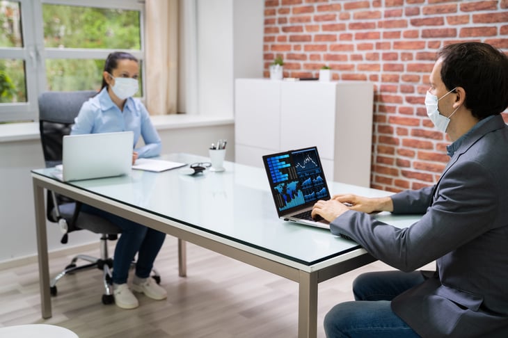 analysts in masks practice social distancing at work