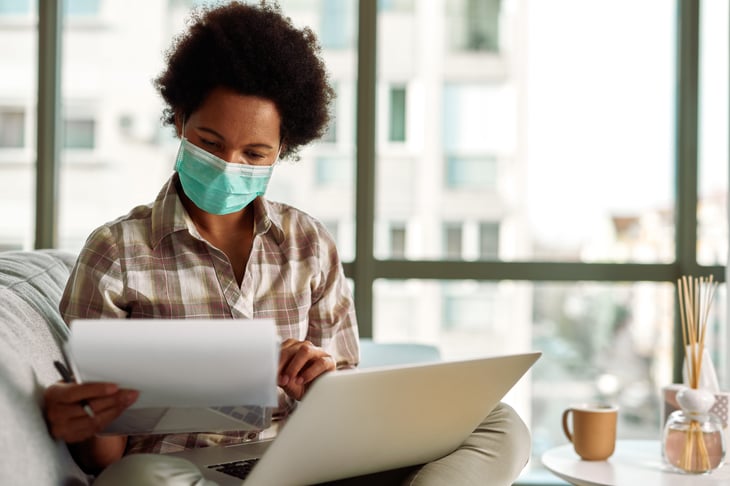 A woman in a mask reviews tax documents