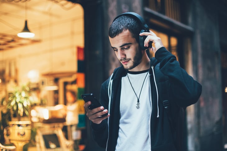 Young man wearing headphones and looking at his phone
