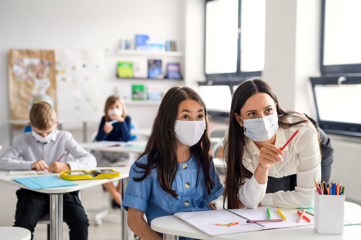 Face mask-wearing students and teacher in a classroom during the coronavirus crisis