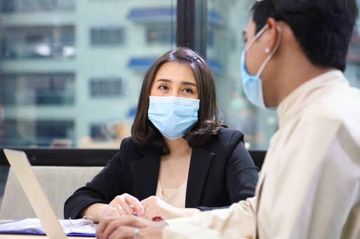 Businesswoman and man wearing masks in a meeting