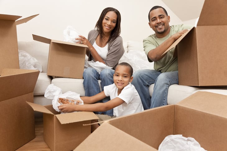 A Black family happily unpacking their home after saving on moving
