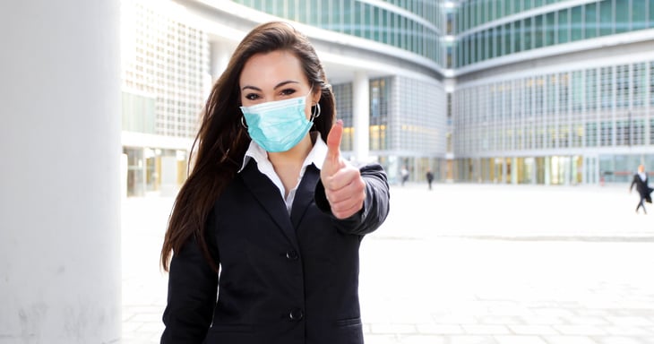 Young female manager wearing a mask gives a thumbs up