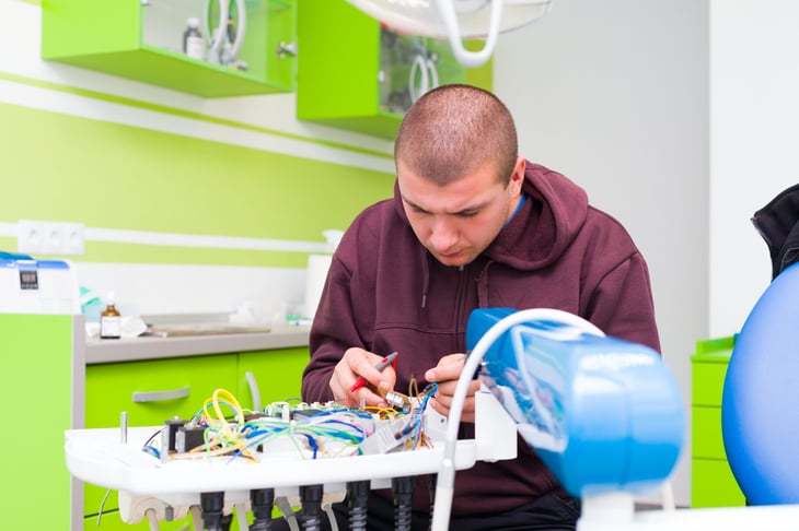 Medical equipment technician fixing a dental chair in a dentist's office.