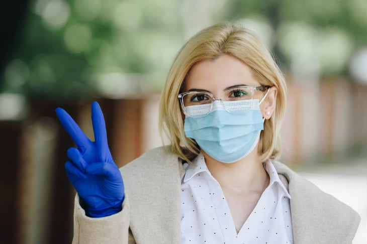 Woman in mask giving peace sign