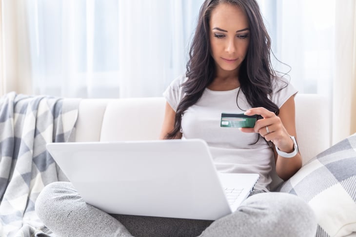 Young woman shopping with her rewards credit card online using her laptop