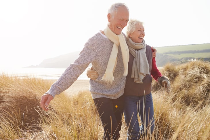 Happy senior couple walking on the beach grass