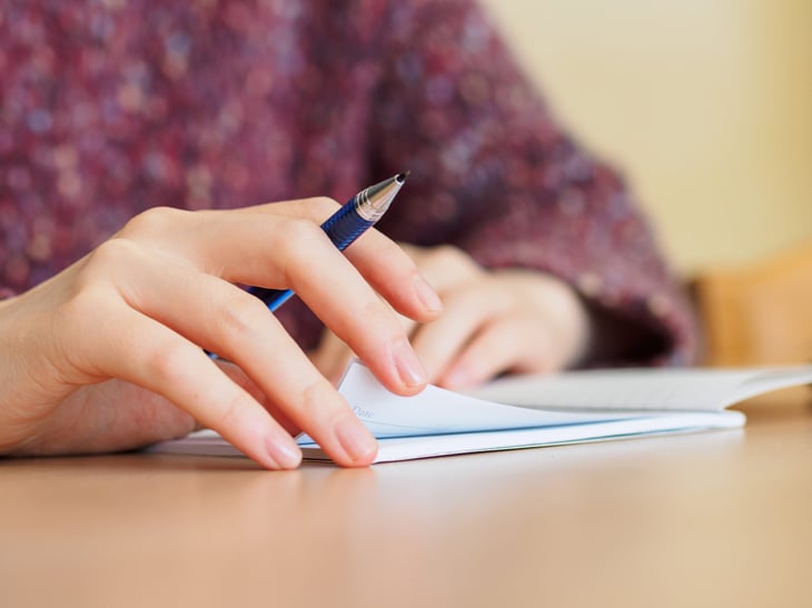 Woman writing in a notebook with a mechanical pencil