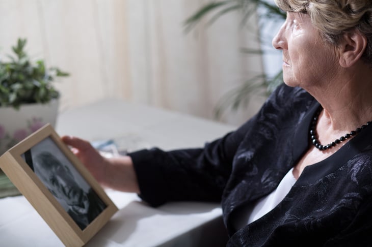 Senior woman holding a photo of her dead husband after a funeral
