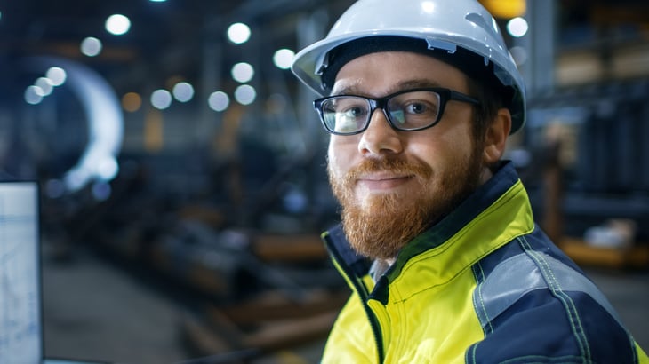 Industrial worker in hardhat working hard but smiling