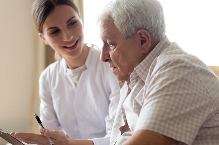 Senior filling out medical paperwork with caregiver
