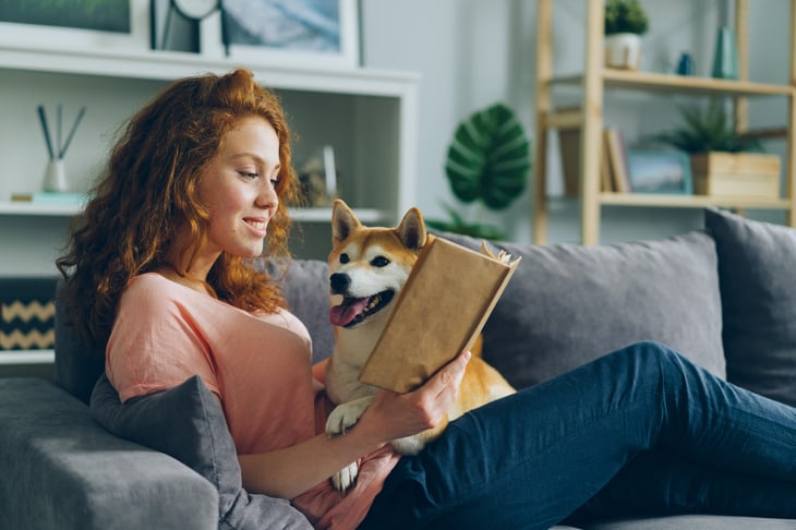 Woman reading a book with her dog