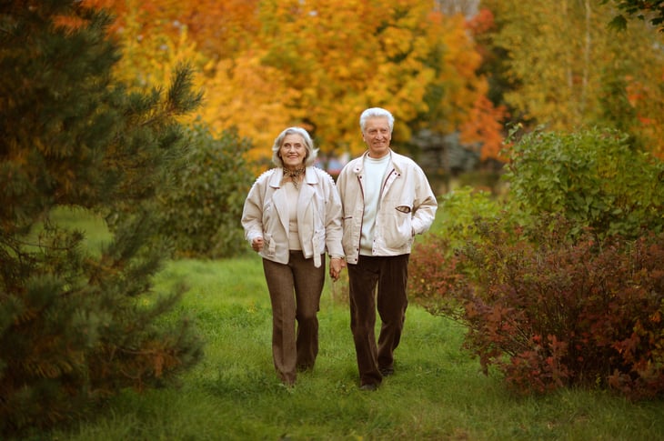 Senior couple walking through the park in autumn