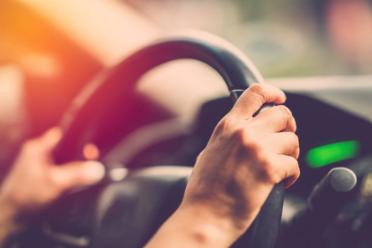 A driver has hands gripping a steering wheel
