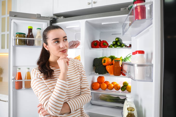Woman thinking about organizing her fridge