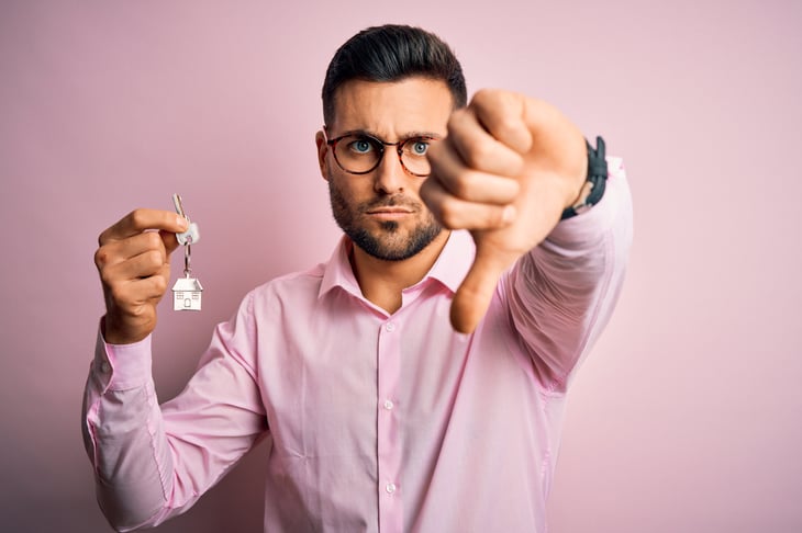 Man with house keys and thumbs down