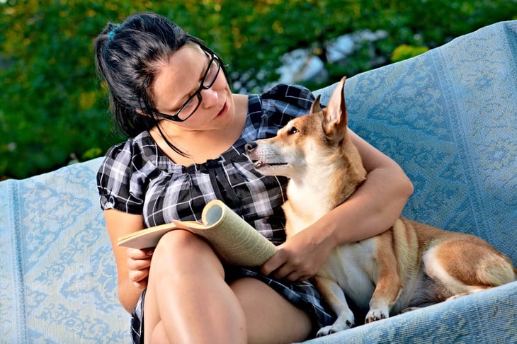 Woman reading a magazine next to her dog
