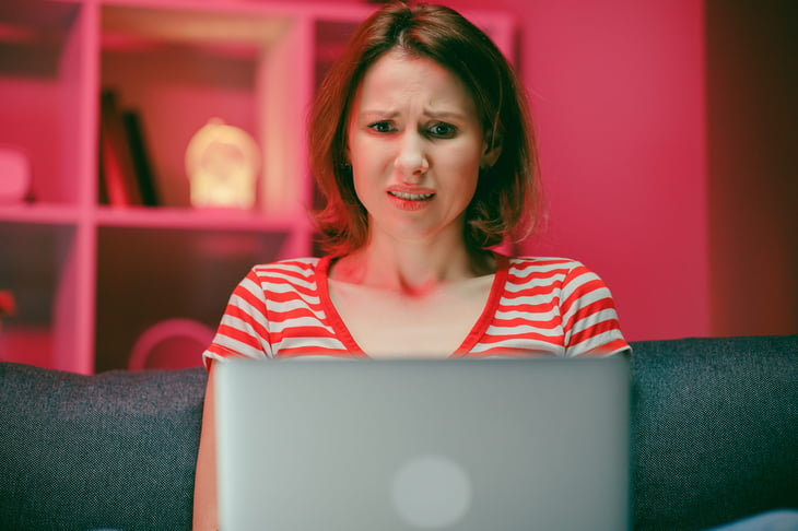 An upset woman is surprised while using a laptop computer