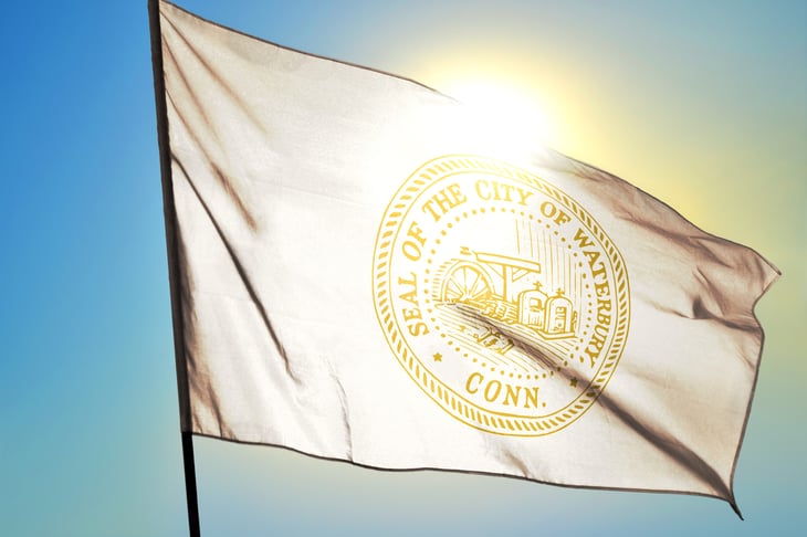 Waterbury of Connecticut of United States flag waving on the wind in front of sun
