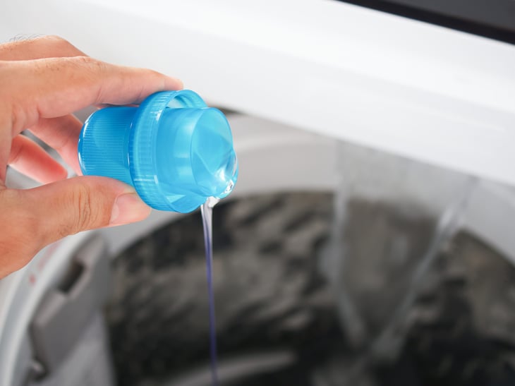Man pouring laundry detergent into a washing machine