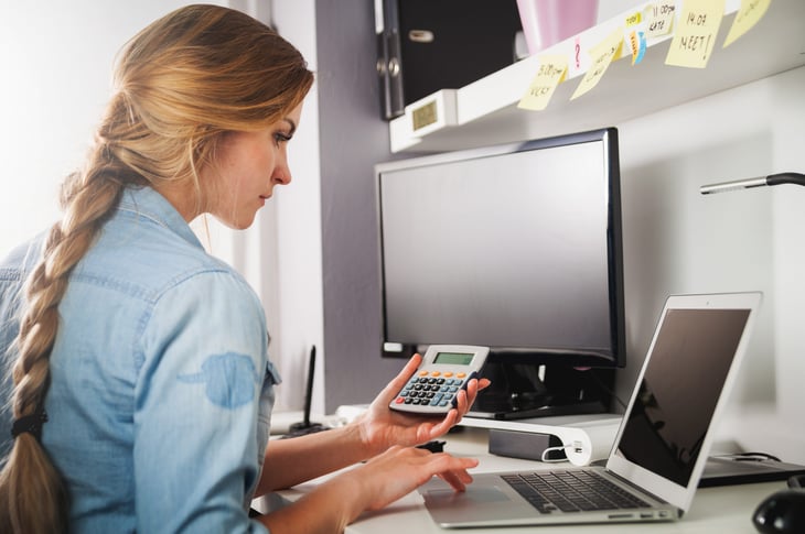 Business woman doing math on calculator and laptop