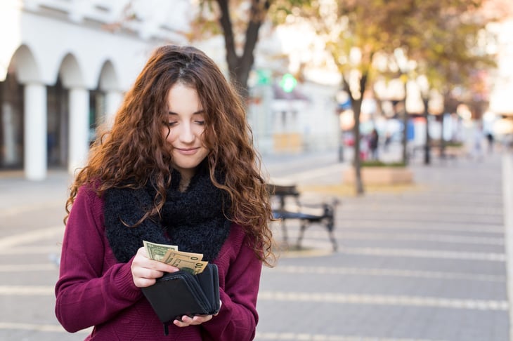 Young woman counts the cash in her wallet from her pay raise