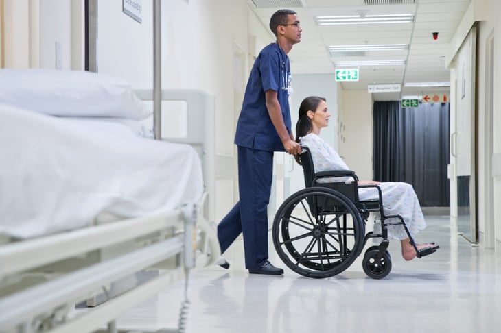 A nurse pushes a patient in a wheelchair