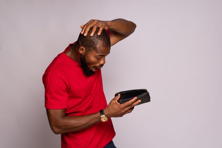 Man looking into empty wallet