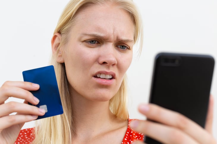 stressed woman holding a phone and credit card