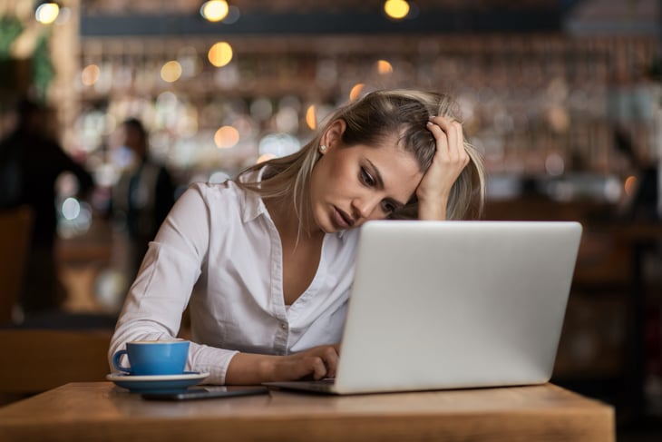 Stressed woman working on a laptop in a coffee shop