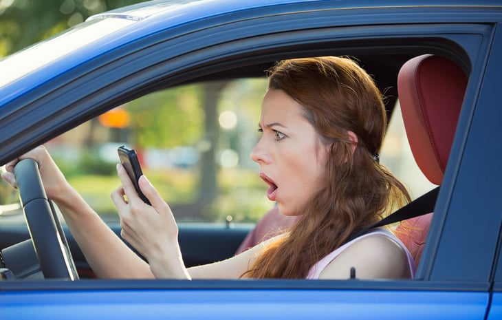 Shocked driver looking at her phone