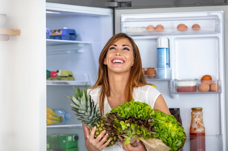 Happy woman putting away groceries