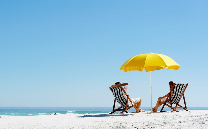 Couple sitting on beach under umbrella