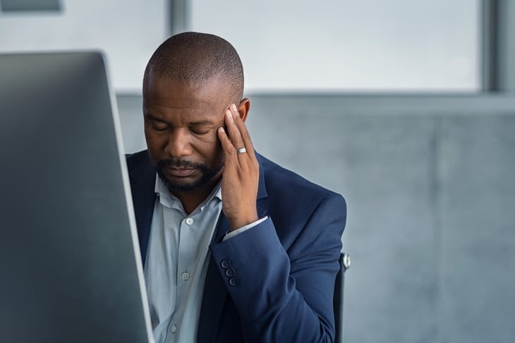 Upset businessman holding his head in front of his computer