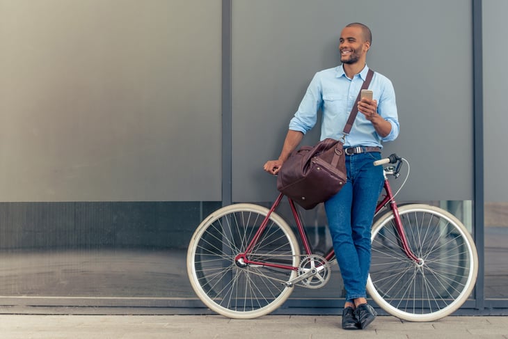 Young man worker on his phone biking to work