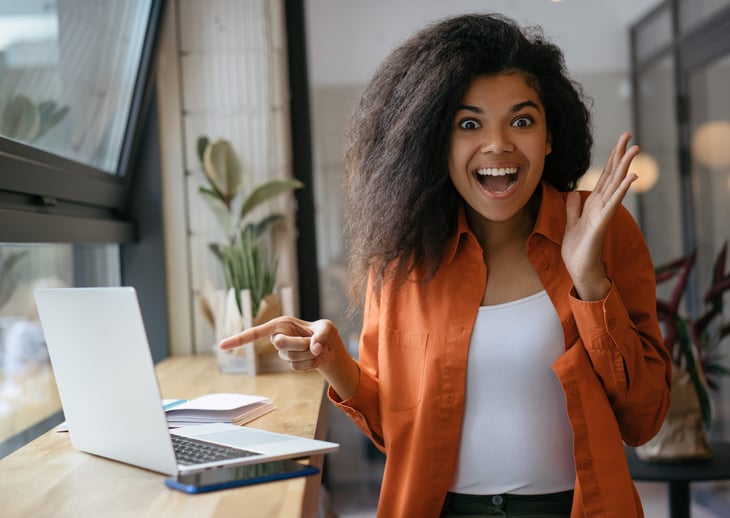 Excited woman pointing at a laptop