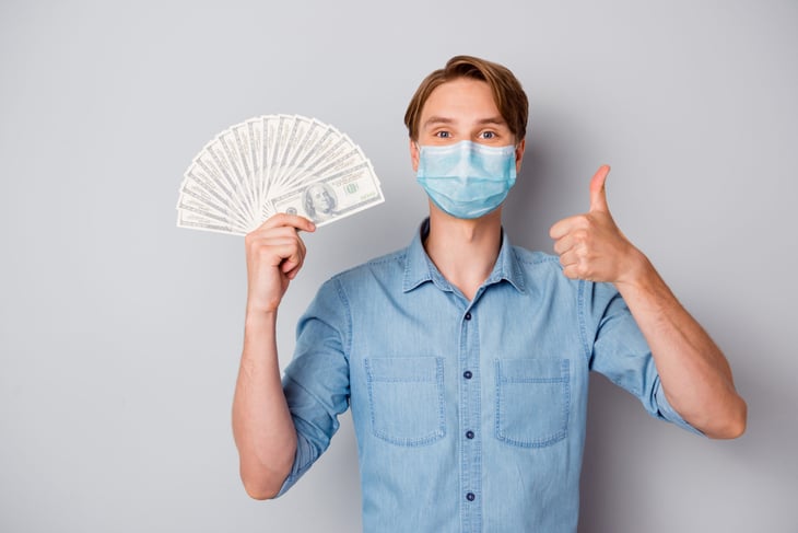 Man in a mask holding stimulus money
