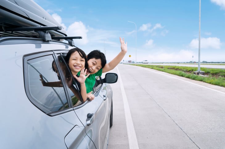 Children waving from an SUV