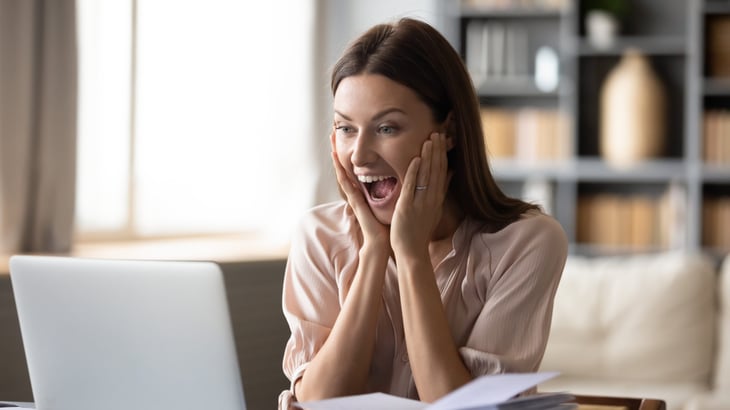 excited woman looking at laptop