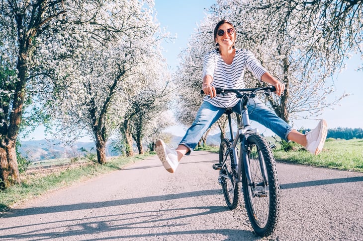 Happy woman riding bike outdoors in spring